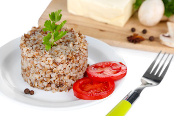 Buckwheat in plate with butter and vegetables isolated on white