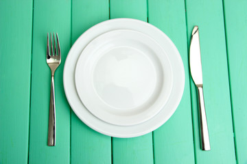 Plate and cutlery on wooden table close-up