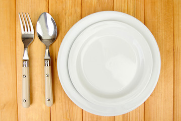 Plate and cutlery on wooden table close-up