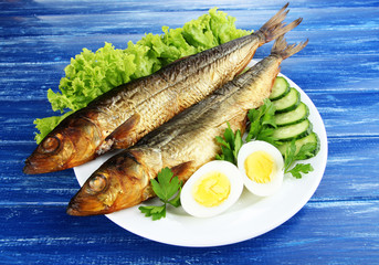 Smoked fish on plate on wooden table