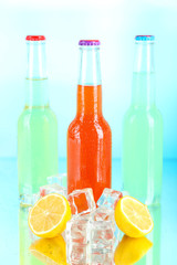Drinks in glass bottles with ice cubes on blue background