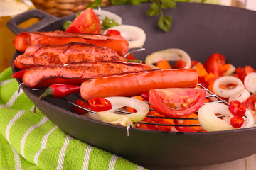 Delicious sausages with vegetables in wok close-up