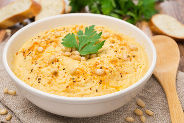 Hummus with pine nuts in a bowl, close-up