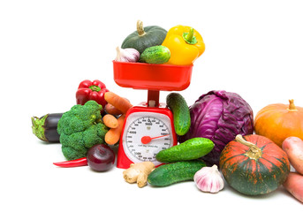 Kitchen scales and fresh vegetables on white background