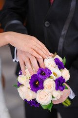 Obraz na płótnie Canvas Hands of the groom and the bride on wedding bouquet