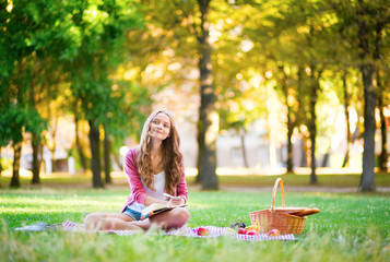 Girl having a picnic and writing in her diary