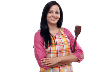 Young Indian woman holding kitchen utensil against white