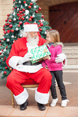 Obraz na płótnie Canvas Santa Claus Giving Gift To Girl