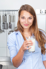 Junge Frau in der Küche trinkt Milch