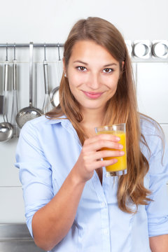Junge Frau in der Küche trinkt Orangensaft