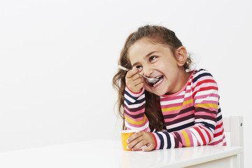 Young girl eating yoghurt in studio