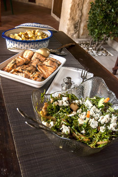 Rustic table with grilled salmon, salad and sauteed potatoes
