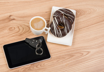 Coffee, donuts and tablet on wooden background