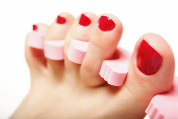 foot pedicure applying red toenails on white