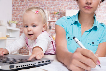 woman with baby in the kitchen working with laptop