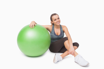 Fototapeta na wymiar Cute woman sitting next to a fitness ball