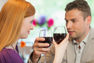 Handsome man having glass of wine with his pretty girlfriend