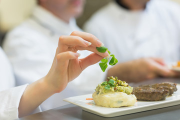 Obraz na płótnie Canvas Female chef garnishing a plate with steak