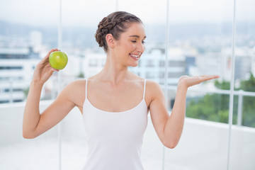 Happy sporty brunette holding green apple