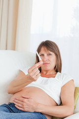 Fototapeta premium Good looking pregnant woman holding a cigarette while lying on a