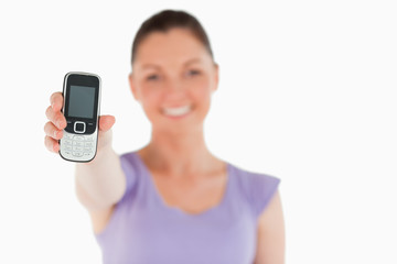 Attractive woman holding and showing her phone while standing