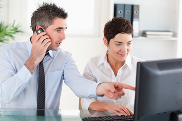 Obraz premium Colleagues working with a computer while using a cellphone