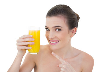 Amused natural brown haired model showing her glass of orange ju