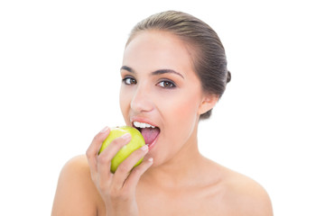 Content young brunette woman biting in a green apple
