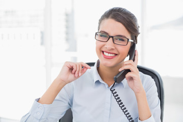 Delighted classy brown haired businesswoman answering the teleph