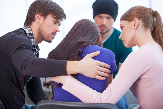 Group of people comforting upset woman.