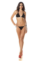attractive and beautiful girl in a black bikini walking on white - obrazy, fototapety, plakaty