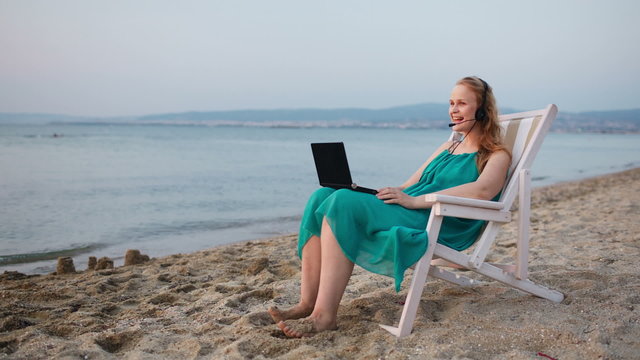 Woman relaxing at the beach with her laptop talking skype