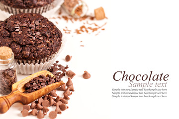 Chocolate muffins and chocolate drops and pieces on white
