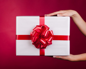 Female hands holding small gift with ribbon.