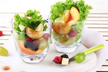 Fruit salad in glasses, on wooden background