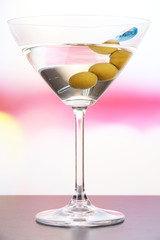 Martini with green olives on table in bar