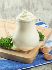 Obraz na płótnie Canvas Sour cream in pitcher on table close-up