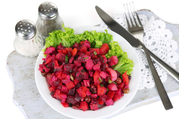 Beet salad on plate on napkin on wooden board isolated on white