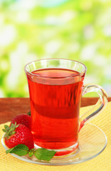 Delicious strawberry tea on table on bright background