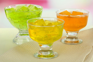 Tasty jelly cubes in bowls on table on light background