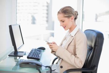 Cheerful blonde businesswoman looking at her phone