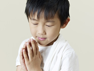 little asian boy praying with clasped hands