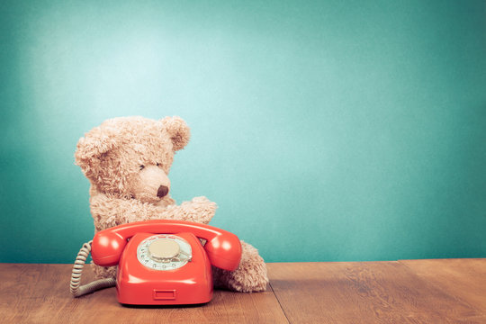 Retro red telephone and Teddy Bear near mint green wall
