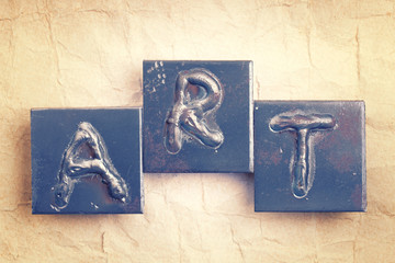 The word "ART" made from metal letters on an old vintage paper b