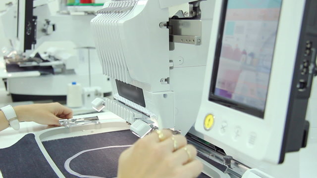 Woman working on computerized machine embroidery
