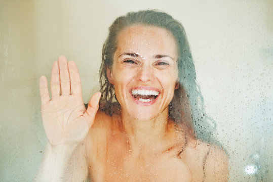 Smiling woman looking through weeping glass in shower door