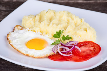 Mashed potatoes with fried eggs and tomato