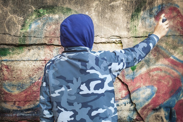 Boy with color spray can near the wall