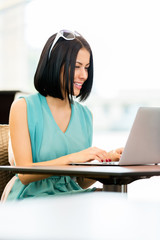 Girl wearing blue dress and sunglasses works at the pc