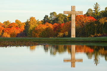 Christian cross in autumn landscape.